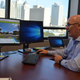 A bespectacled engineer sits in front of a computer displaying an image of a Miami street awash in simulated flood water.